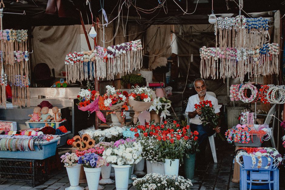 A street flower stall featuring a variety of fresh floral arrangements and accessories. The stall displays bouquets of red, white, pink, and purple flowers, including roses, daisies, and lilies, arran